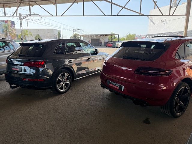 Vista lateral del Audi SQ5 gris y Porsche Macan rojo en Chevicars